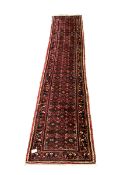 Central Asian runner rug, with repeating lozenge motif on busy red field, stylised foliate to border