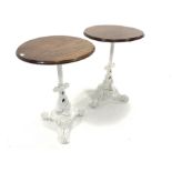 Pair of Victorian design cast iron tables, with circular mahogany tops raised on raised in column an