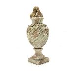 Lidded terracotta urn, the wrythen body supported by a socle on square base, well weathered and with