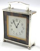Silver cased mantle clock with white dial surrounded by tortoiseshell banding with loop handle and b