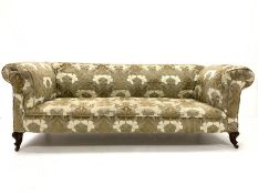 Late Victorian drop arm chesterfield sofa upholstered in textured floral fabric, raised on walnut le