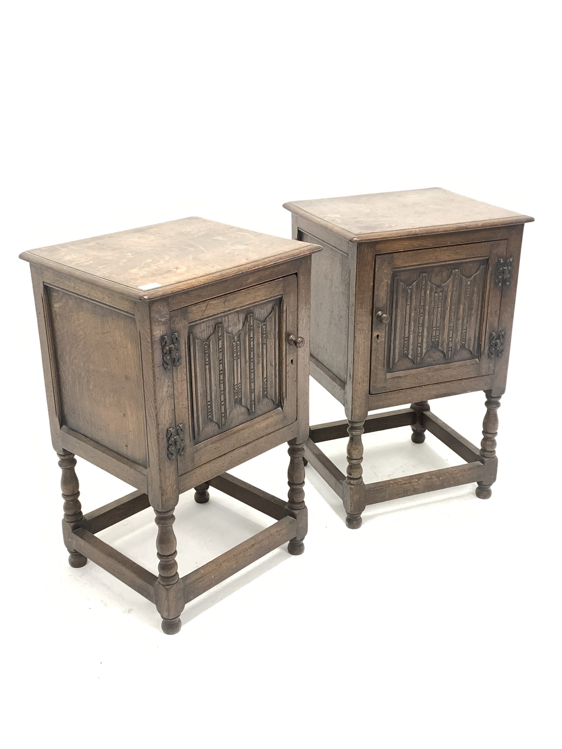 Pair of early 20th century oak bedside cupboards, with fielded panelled doors carved with linen fold