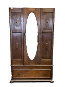 Early 20th century oak single wardrobe, with bevelled oval mirror enclosing interior fitted for hang