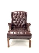 20th century George III style wing back armchair, upholstered in deep buttoned and studded ox blood