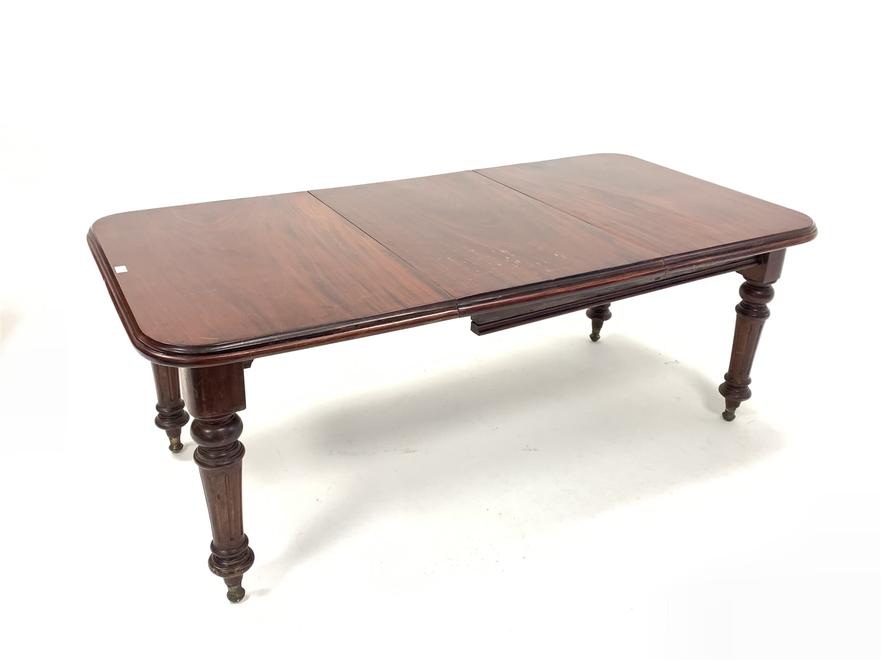 Edwardian mahogany extending dining table, moulded top raised on turned and fluted supports terminat