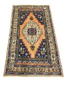 Persian ground rug, with central medallion of blues, greens, reds, and ivory, on an orange field, en