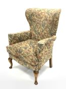 20th century wing back armchair, with swept arms, squab cushion upholstered in scrolled floral fabri