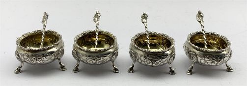 Set of four Victorian silver circular salts with embossed decoration, gilded interiors and shaped su