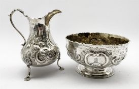Victorian silver cream jug with embossed floral decoration and engraved with a crest on shaped suppo