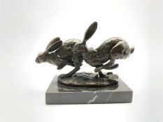Bronze figure group, modelled as two hares in chase, signed Nick and with foundry mark, raised upon