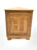 Yorkshire oak floor standing corner cupboard, with sngle fielded panelled door carved with floral de