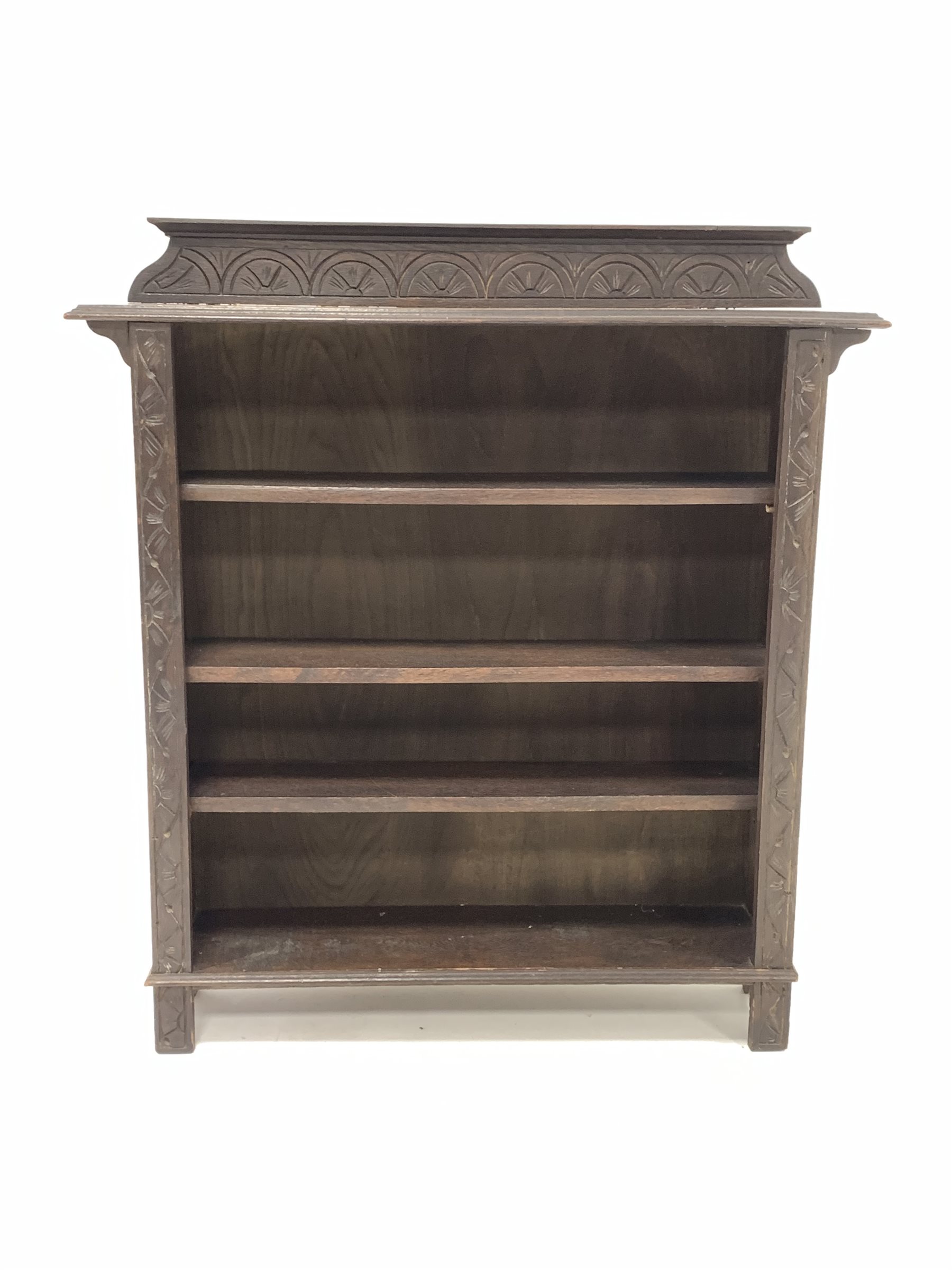 Early 20th century dark oak open bookcase, the raised back with lunette carving over three adjustabl