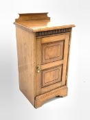 Edwardian walnut bedside cupboard, raised back over carved frieze and panelled door enclosing one sh