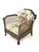 Early 20th century polished beech carved bergere armchair, shaped cresting rail and out swept arms o