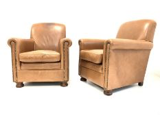 Pair of armchairs, upholstered in studded tan leather, raised on turned front supports