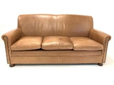 Traditional brown studded leather upholstered three seat sofa, with squab cushions, raised on turned