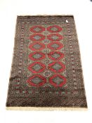 Persian design grey ground Bokhara rug, repeating red and blue gul motif, enclosed by multi line bor