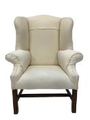 George III style mahogany framed wingback armchair, upholstered in natural linen, with shapely swept