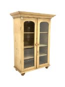 Victorian pine bookcase, projecting cornice over two arched glazed doors enclosing three adjustable