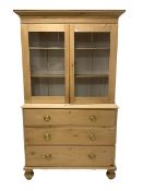 Victorian polished pine cabinet on chest, projecting cornice over two glazed doors enclosing interio