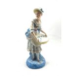 Late 19th century French standing figure of a girl holding a large basket on a blue base