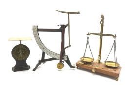 Set of brass balance scales and five weights on wooden base