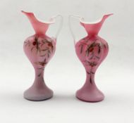 Pair of 19th/ early 20th century pink satin glass ewers painted with floral sprays