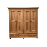 Solid pine four door wardrobe enclosing interior fitted for hanging