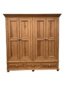 Solid pine four door wardrobe enclosing interior fitted for hanging