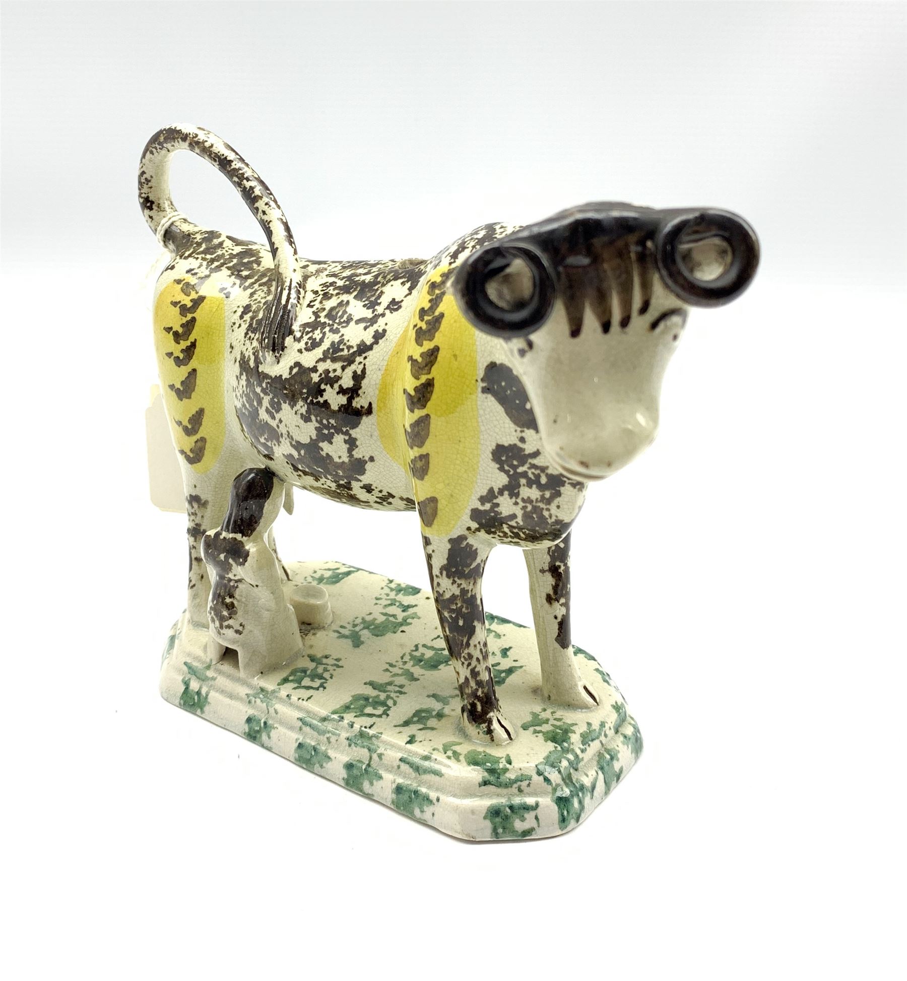 19th century Pratt type cow creamer sponged in black and yellow with seated milk maid on an octagona