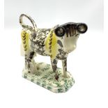 19th century Pratt type cow creamer sponged in black and yellow with seated milk maid on an octagona