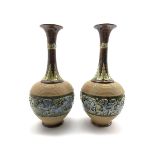 Pair of Doulton Lambeth bottle shape vases decorated with a raised band of flowers on a green and br