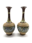 Pair of Doulton Lambeth bottle shape vases decorated with a raised band of flowers on a green and br