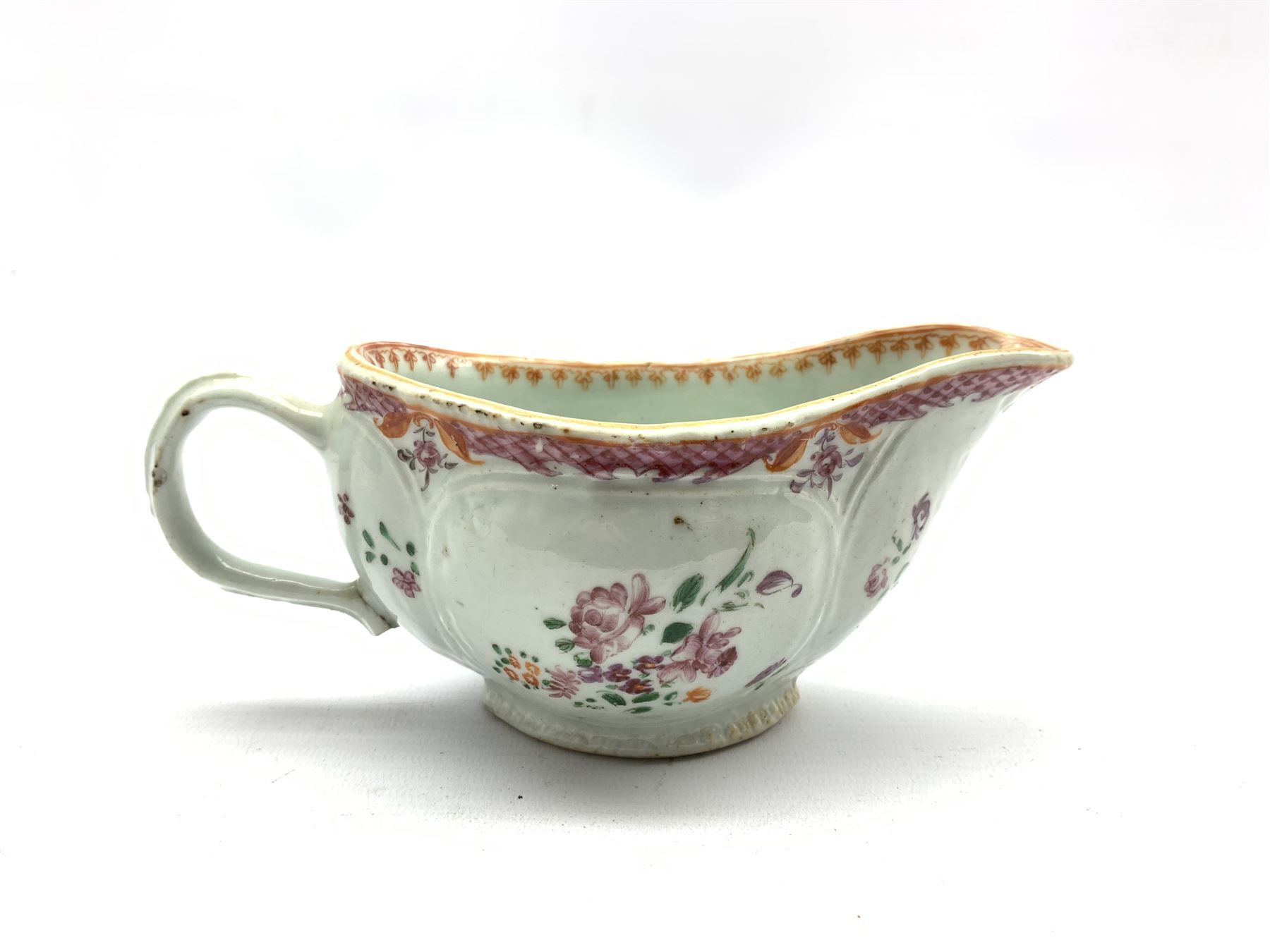 18th century porcelain sauceboat hand-painted with floral sprays beneath a pink scale border