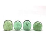 Four Victorian green glass dump paperweights with internal flower inclusion