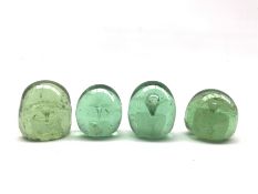 Four Victorian green glass dump paperweights with internal flower inclusion
