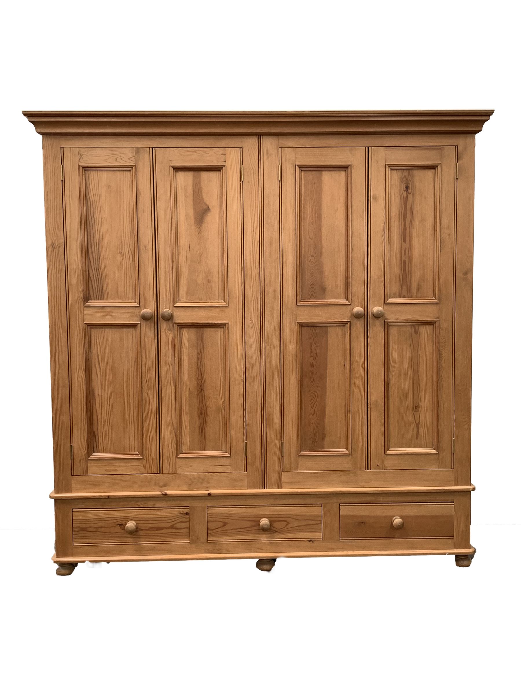 Solid pine four door wardrobe enclosing interior fitted for hanging