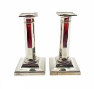 Pair of George V silver candlesticks with panel sided columns and stepped square bases