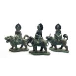 Three Chinese patinated bronze figures modelled as a Deity seated on the back of an Elephant and two