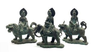 Three Chinese patinated bronze figures modelled as a Deity seated on the back of an Elephant and two