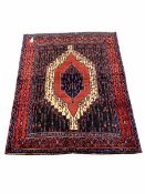 Persian senneh hand knotted red ground rug centred by a geometric medallion and bordered 165cm x 120