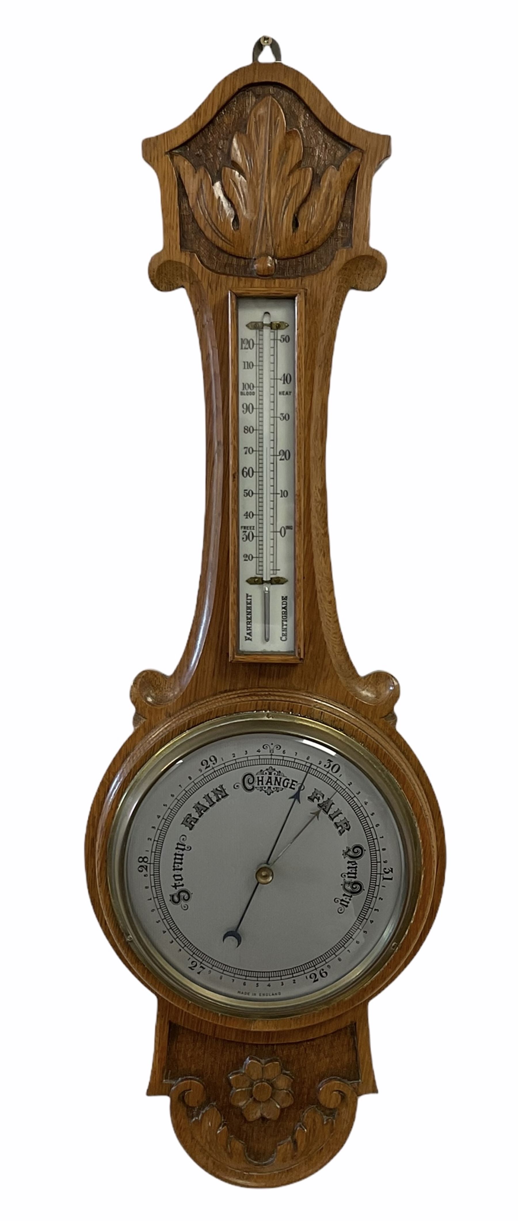 An English 1930�s solid oak carved hall barometer in a scroll shaped carved case with applied floral