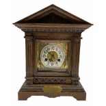 An early twentieth century German oak mantle clock in an architectural case on a shaped plinth with