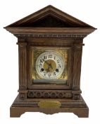 An early twentieth century German oak mantle clock in an architectural case on a shaped plinth with