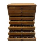 An eight drawer printers chest containing a quantity of metal stamps/ matrices