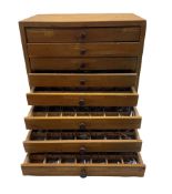 An eight drawer printers chest containing a quantity of metal stamps/ matrices