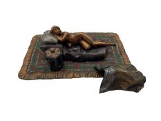 A cold painted bronze of a reclining nude lady on a rug in the manner of Bergman