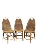 Set of three mid century wicker chairs raised on bamboo supports