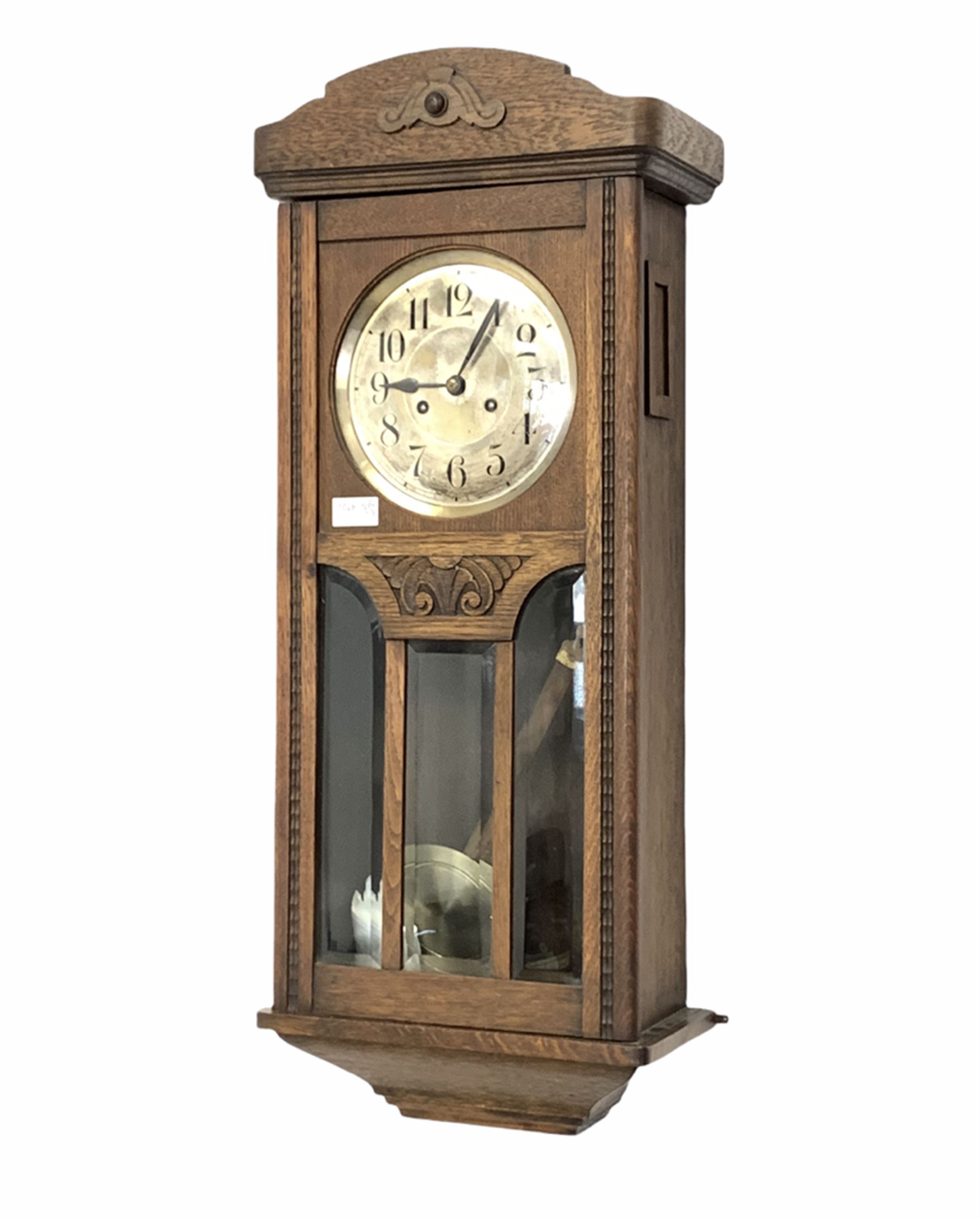 A 1930's oak cased wall clock with an eight-day movement striking the hours and half-hours on a coil