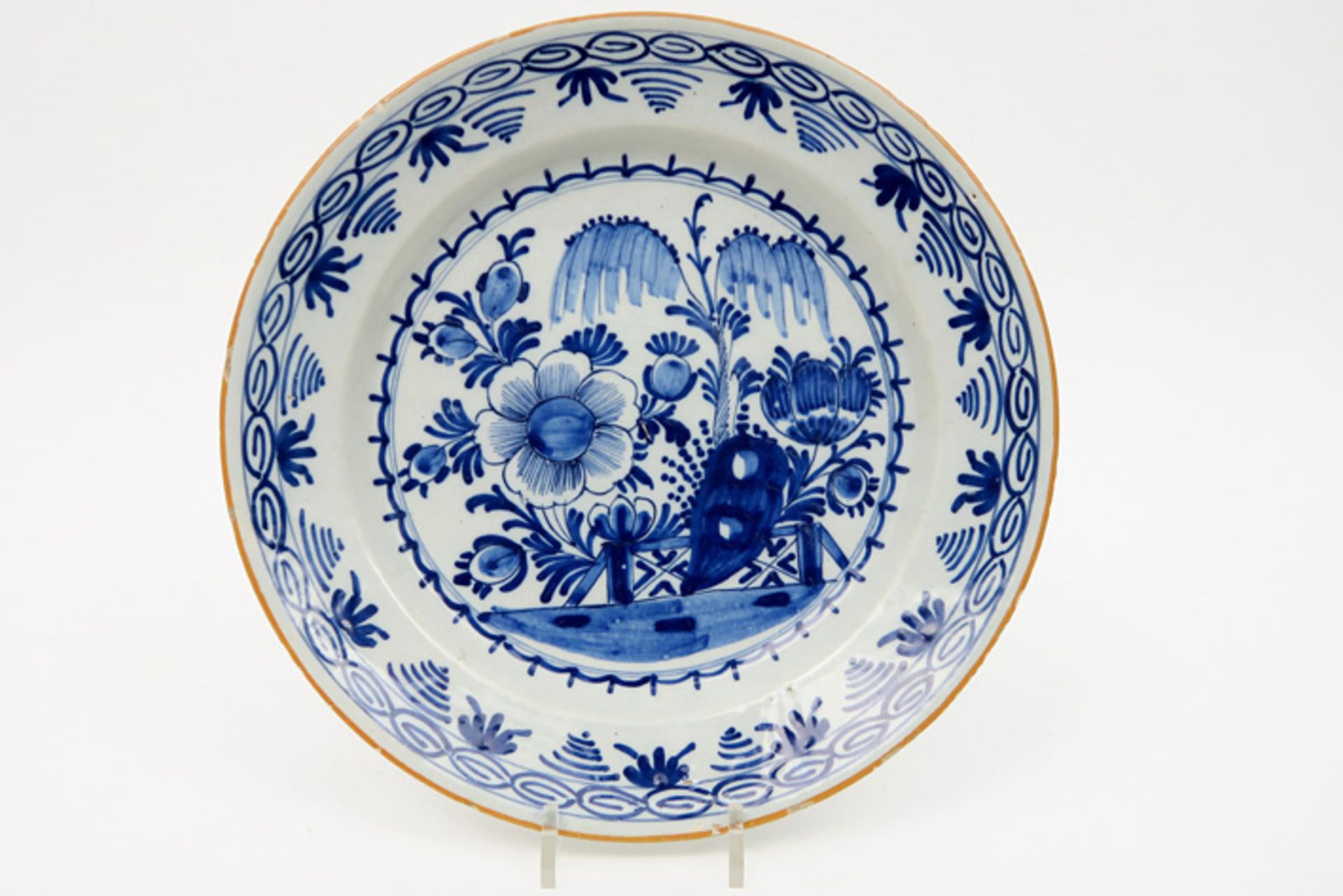 quite big 18th Cent. dish in ceramic from Delft with a blue-white peacock in garden decor Achttiende